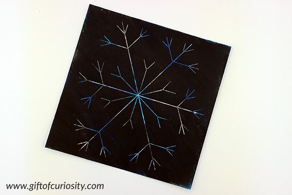 Snowflake scratch art using DIY scratch paper made with Kwikstix Thin Stix. I can't believe how easy and mess-free it is to make scratch paper with these solid tempera paints! And the snowflake art looks beautiful. This is a great winter art project to try with the kids. || Gift of Curiosity
